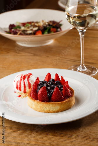 Obraz na płótnie Berry tartlets with curd cream on a wooden background. Summer fruit baking. Tartlets with raspberries, blueberries and red currants. Served with ice cream. w salonie