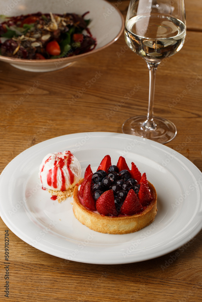 Berry tartlets with curd cream on a wooden background. Summer fruit baking. Tartlets with raspberries, blueberries and red currants. Served with ice cream.