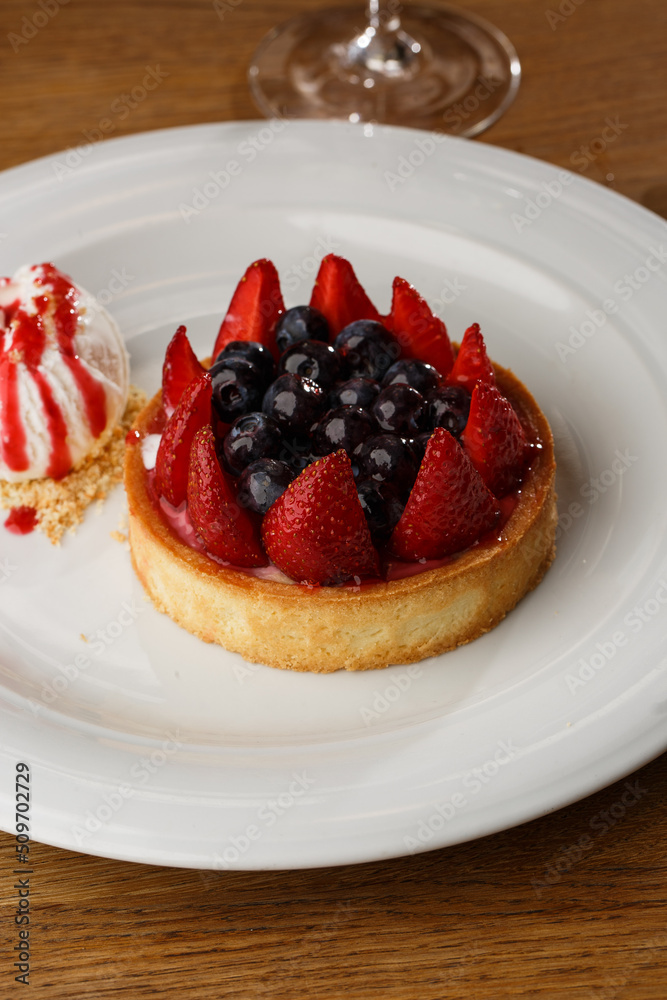 Berry tartlets with curd cream on a wooden background. Summer fruit baking. Tartlets with raspberries, blueberries and red currants. Served with ice cream.