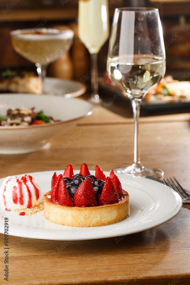 Berry tartlets with curd cream on a wooden background. Summer fruit baking. Tartlets with raspberries, blueberries and red currants. Served with ice cream.