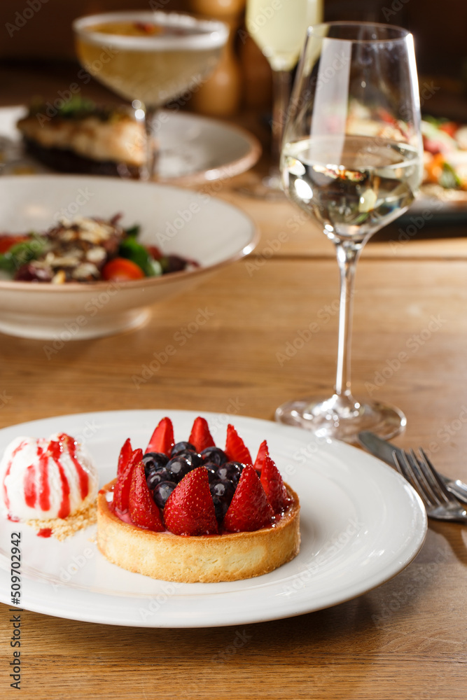 Berry tartlets with curd cream on a wooden background. Summer fruit baking. Tartlets with raspberries, blueberries and red currants. Served with ice cream.