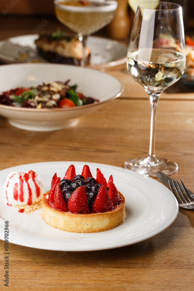 Berry tartlets with curd cream on a wooden background. Summer fruit baking. Tartlets with raspberries, blueberries and red currants. Served with ice cream.