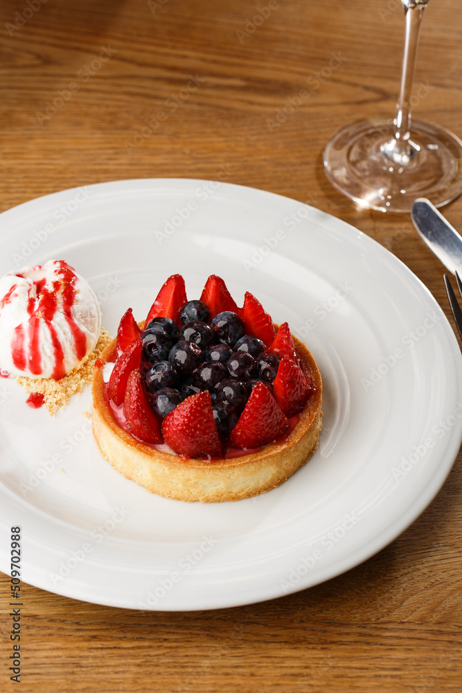 Berry tartlets with curd cream on a wooden background. Summer fruit baking. Tartlets with raspberries, blueberries and red currants. Served with ice cream.