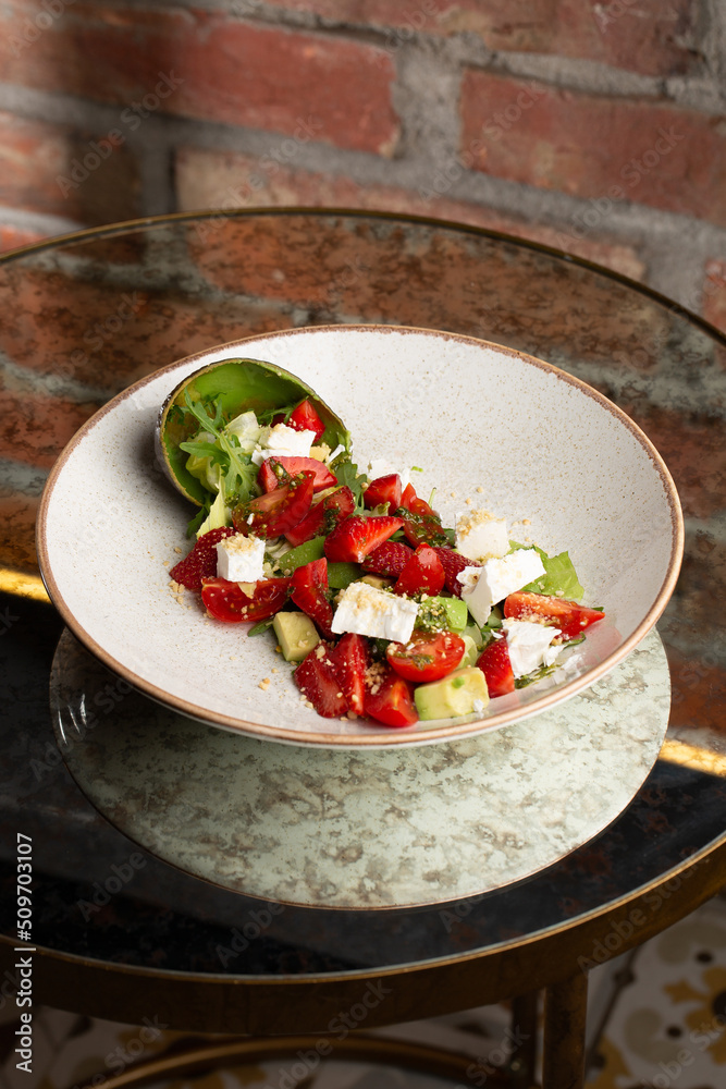 Tasty and healthy salad with arugula, brie cheese, avocado, cherry tomatoes and strawberry. Top view. The flat lay. Banner