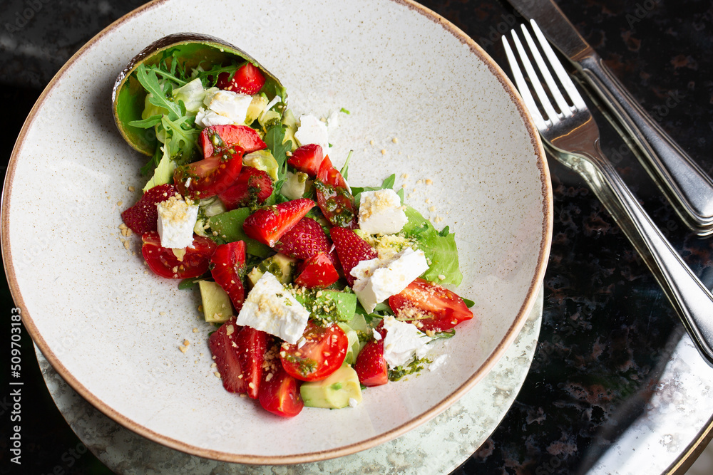 Tasty and healthy salad with arugula, brie cheese, avocado, cherry tomatoes and strawberry. Top view. The flat lay. Banner