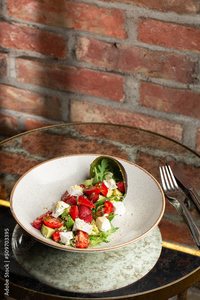 Tasty and healthy salad with arugula, brie cheese, avocado, cherry tomatoes and strawberry. Top view. The flat lay. Banner
