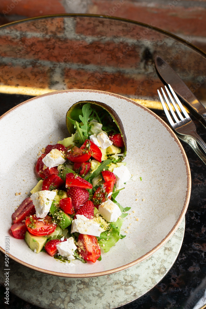 Tasty and healthy salad with arugula, brie cheese, avocado, cherry tomatoes and strawberry. Top view. The flat lay. Banner