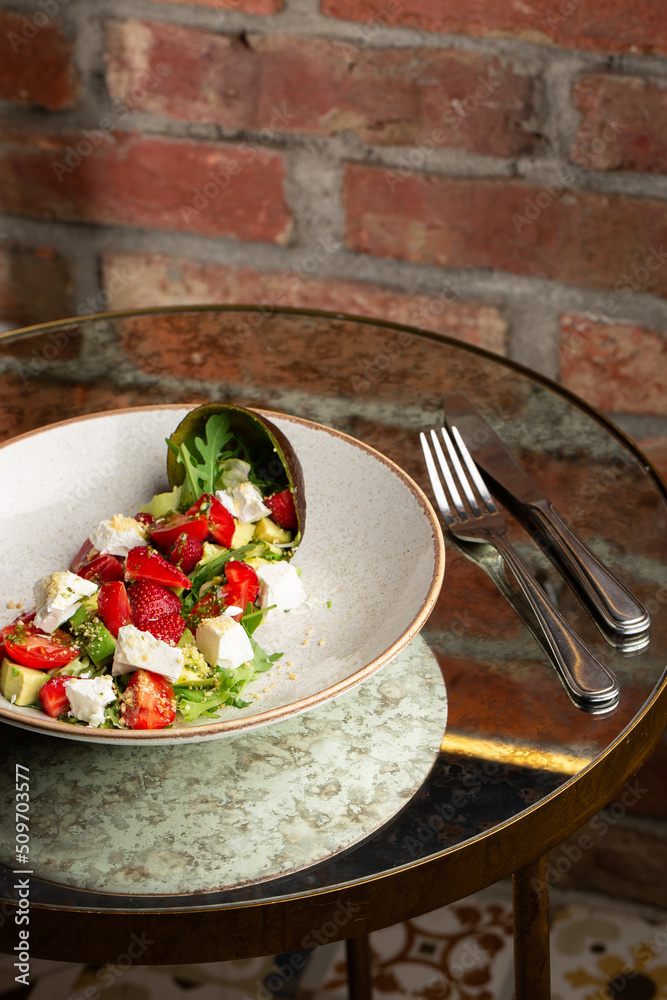 Tasty and healthy salad with arugula, brie cheese, avocado, cherry tomatoes and strawberry. Top view. The flat lay. Banner