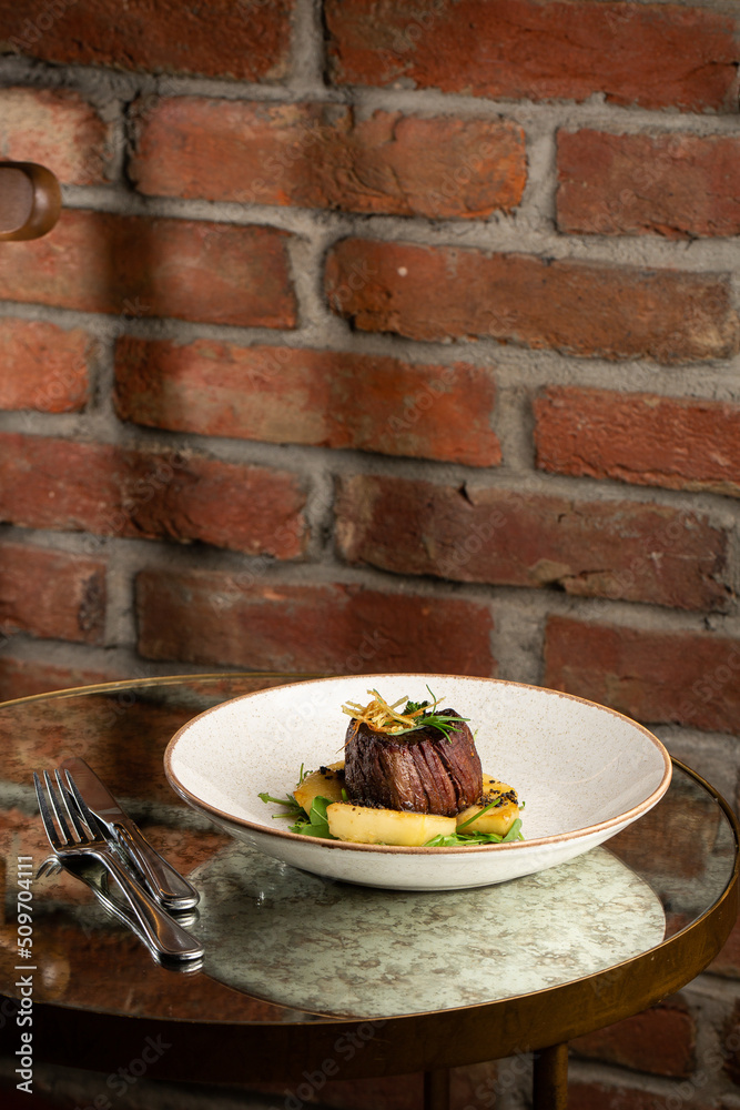 Grilled meat fillet steak medallion with green sauce, served with pear or apple. On dark background