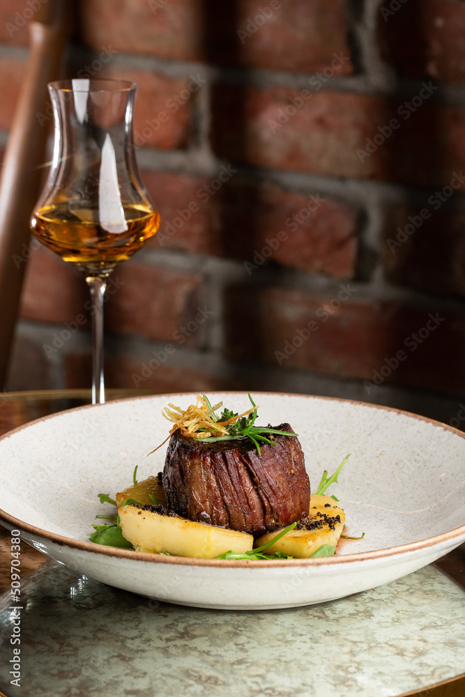 Grilled meat fillet steak medallion with green sauce, served with pear or apple. On dark background