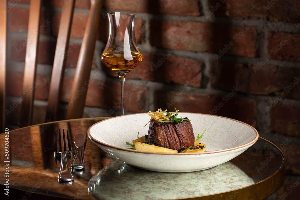 Grilled meat fillet steak medallion with green sauce, served with pear or apple. On dark background