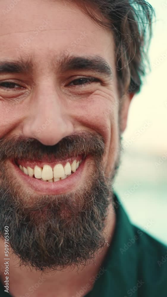 VERTICAL VIDEO: Close-up portrait of a smiling man with a beard on the embankment. Frontal closeup portrait of happy young hipster male looking at camera VERTICAL VIDEO: Close-up portrait of a smiling man with a beard on the embankment. Frontal closeup portrait of happy young hipster male looking at camera