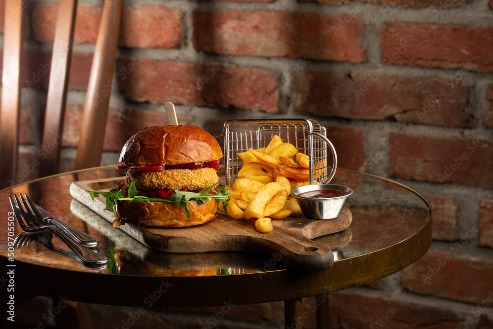 Big cheeseburger with french fries. Hamburger with beef patty onion, tomato, lettuce pickles, melted cheddar, mustards, tomato jam, mayo