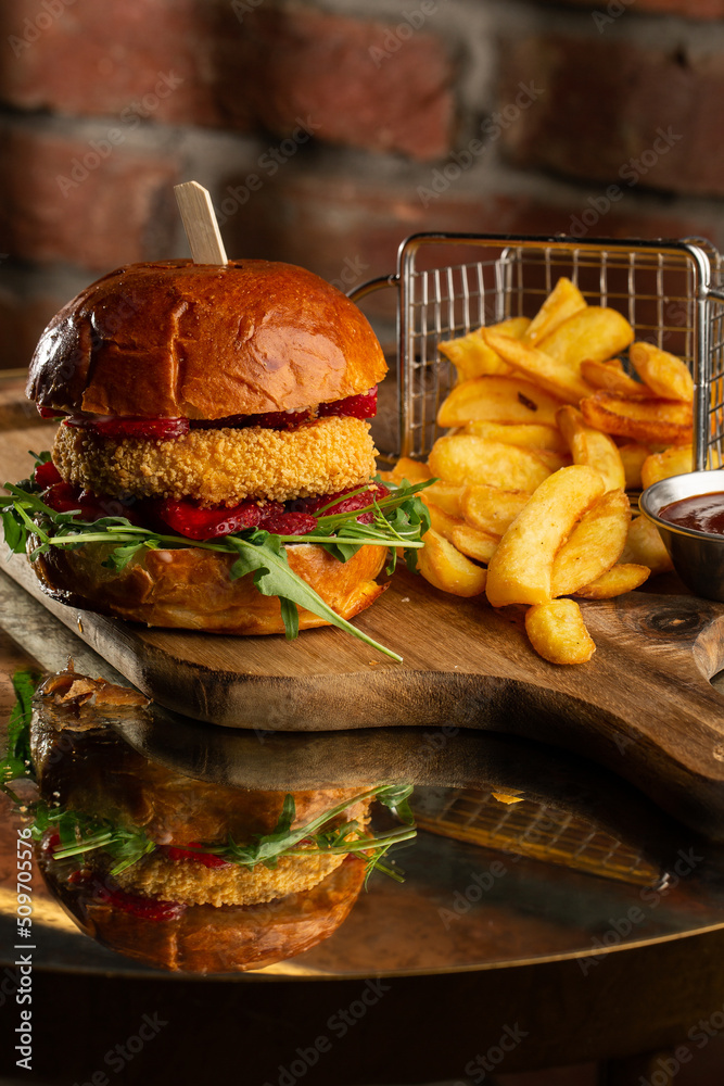 Big cheeseburger with french fries. Hamburger with beef patty onion, tomato, lettuce pickles, melted cheddar, mustards, tomato jam, mayo
