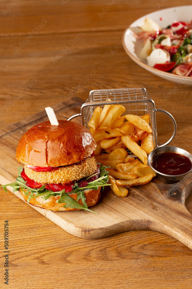 Big cheeseburger with french fries. Hamburger with beef patty onion, tomato, lettuce pickles, melted cheddar, mustards, tomato jam, mayo