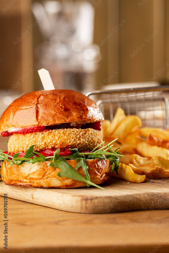 Big cheeseburger with french fries. Hamburger with beef patty onion, tomato, lettuce pickles, melted cheddar, mustards, tomato jam, mayo