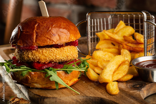 Big cheeseburger with french fries. Hamburger with beef patty onion, tomato, lettuce pickles, melted cheddar, mustards, tomato jam, mayo