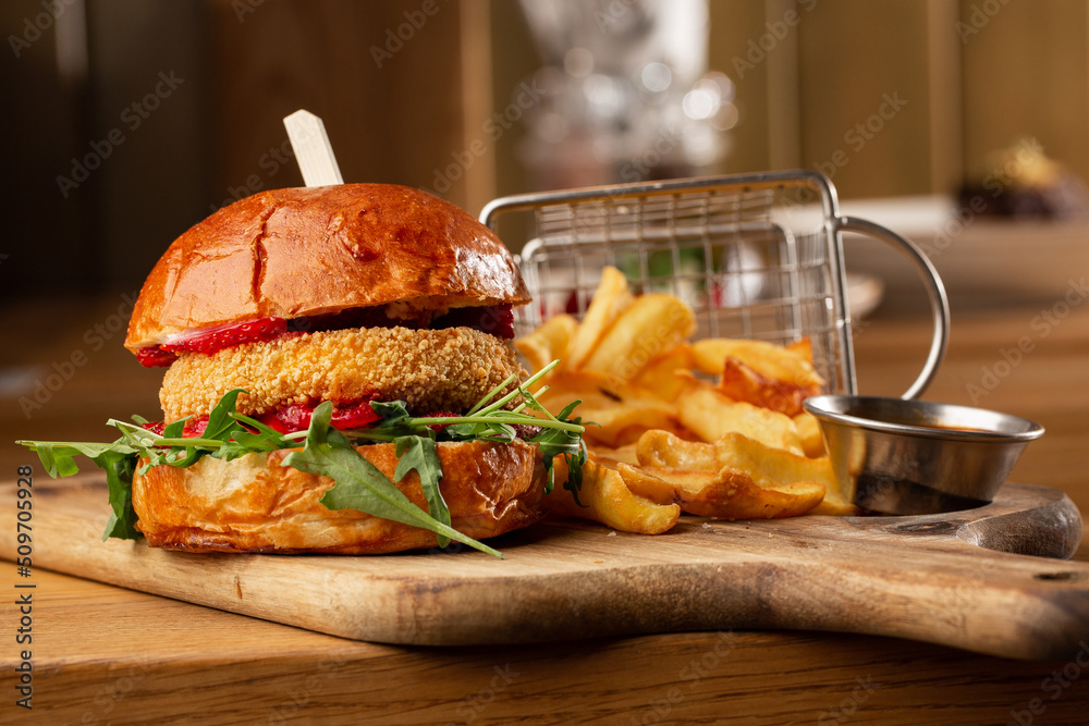 Big cheeseburger with french fries. Hamburger with beef patty onion, tomato, lettuce pickles, melted cheddar, mustards, tomato jam, mayo