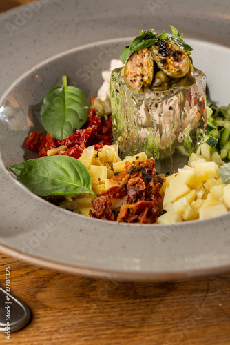 Obraz na płótnie Closeup of cold soup okroshka with beef, vegetables and kefir served in a white bowl, selective focus. Summer, cold soup with cucumber, radish, egg, potatoes and fresh herbs seasoned with kefir. w salonie