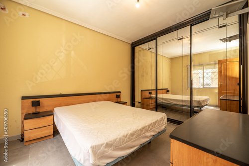 Double bedroom with plywood furniture and wardrobe with sliding mirror doors with black details to match the furniture