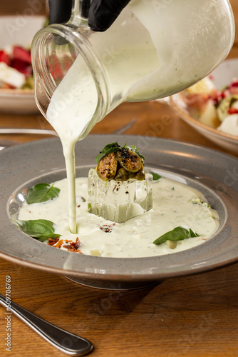 Obraz na płótnie Closeup of cold soup okroshka with beef, vegetables and kefir served in a white bowl, selective focus. Summer, cold soup with cucumber, radish, egg, potatoes and fresh herbs seasoned with kefir. w salonie