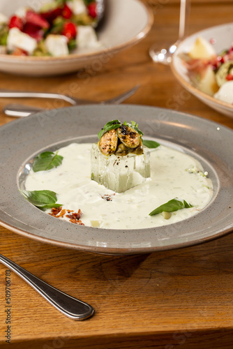 Obraz na płótnie Closeup of cold soup okroshka with beef, vegetables and kefir served in a white bowl, selective focus. Summer, cold soup with cucumber, radish, egg, potatoes and fresh herbs seasoned with kefir. w salonie
