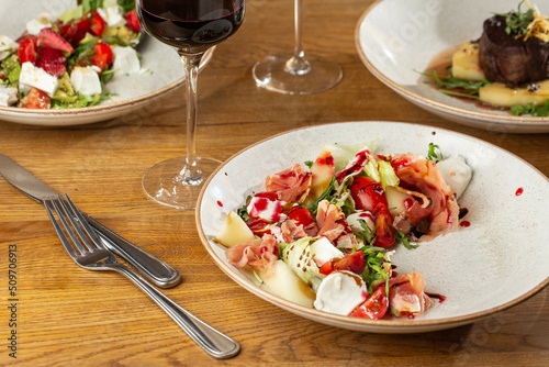 Obraz na płótnie Prosciutto crudo ham salad with mozzarella cheese and arugula on a plate. Bright background. Top view. Copy space w salonie