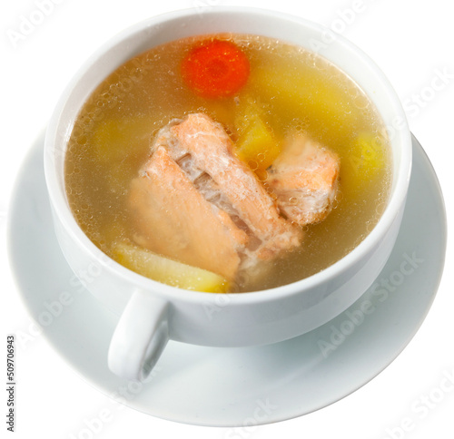 Appetizing rich salmon backbone soup with potatoes and carrots served in white tureen with crispy toasts. Isolated over white background photo