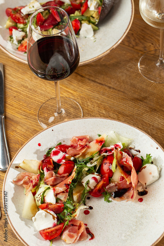 Obraz na płótnie Prosciutto crudo ham salad with mozzarella cheese and arugula on a plate. Bright background. Top view. Copy space w salonie
