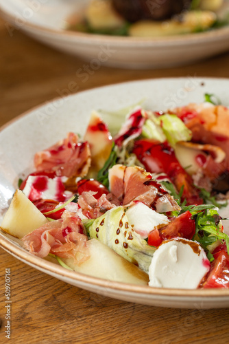 Obraz na płótnie Prosciutto crudo ham salad with mozzarella cheese and arugula on a plate. Bright background. Top view. Copy space w salonie