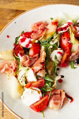 Obraz na płótnie Prosciutto crudo ham salad with mozzarella cheese and arugula on a plate. Bright background. Top view. Copy space w salonie