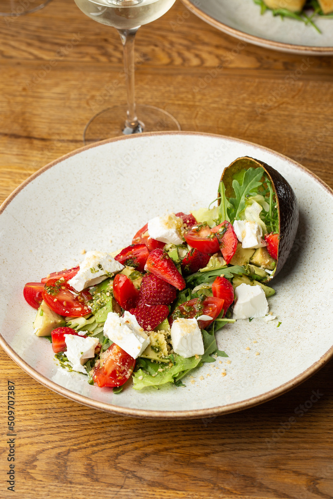 Tasty and healthy salad with arugula, brie cheese, avocado, cherry tomatoes and strawberry. Top view. The flat lay. Banner
