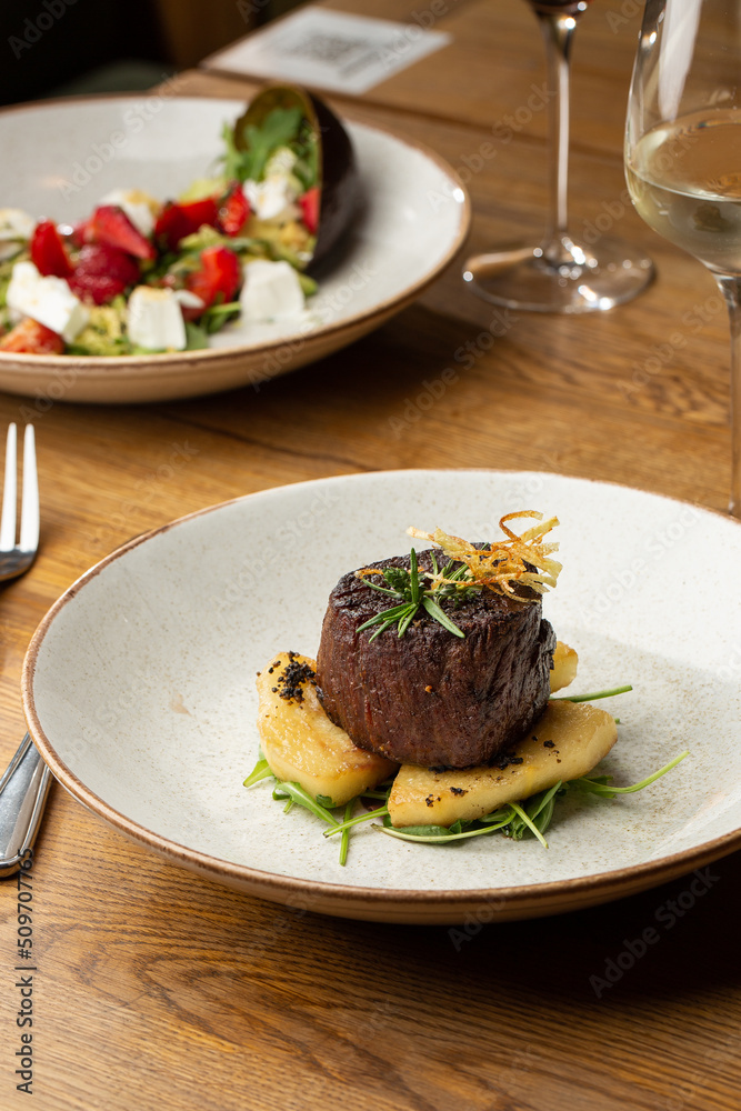 Grilled meat fillet steak medallion with green sauce, served with pear or apple. On dark background