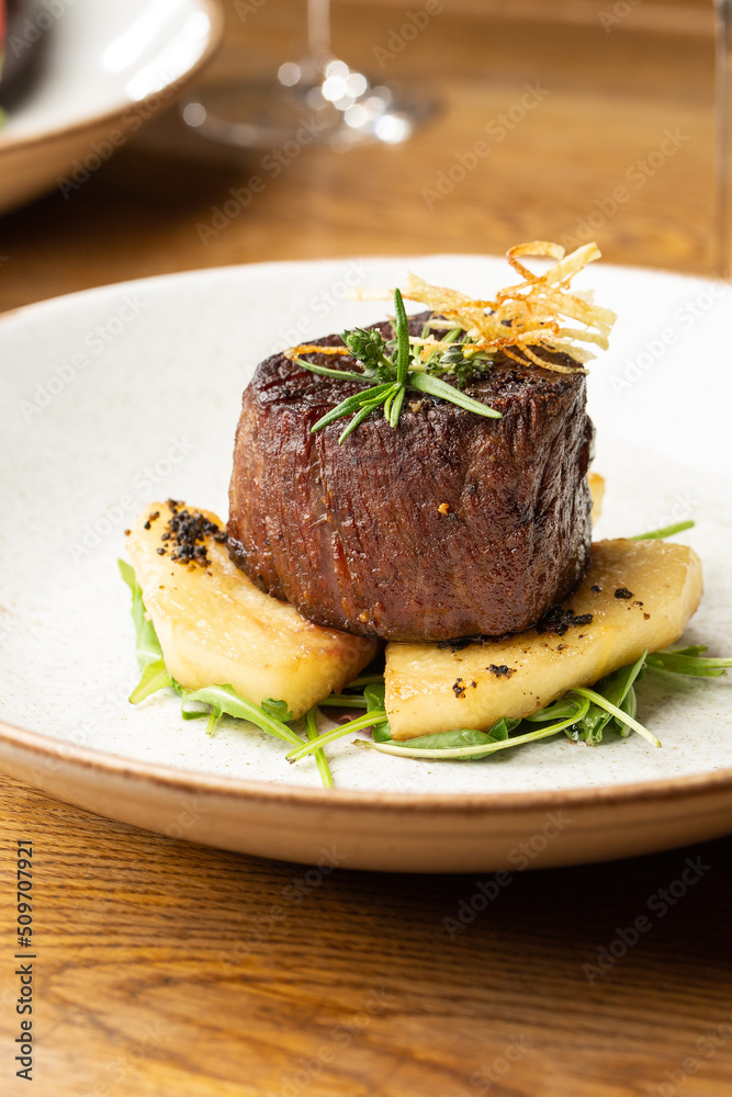 Grilled meat fillet steak medallion with green sauce, served with pear or apple. On dark background