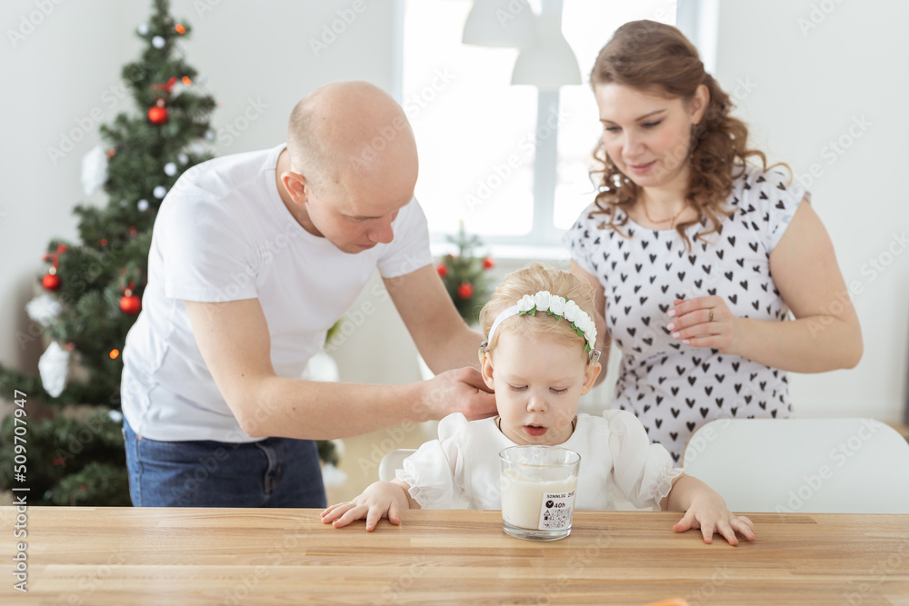 Mother and father helps to put on cochlear implant for their deaf baby daughter in christmas living room. Hearing aid and innovating medical technologies treatment deafness concept Mother and father helps to put on cochlear implant for their deaf baby daughter in christmas living room. Hearing aid and innovating medical technologies treatment deafness concept