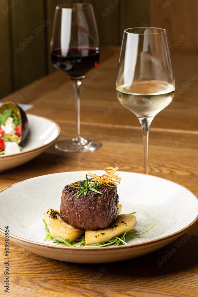Grilled meat fillet steak medallion with green sauce, served with pear or apple. On dark background