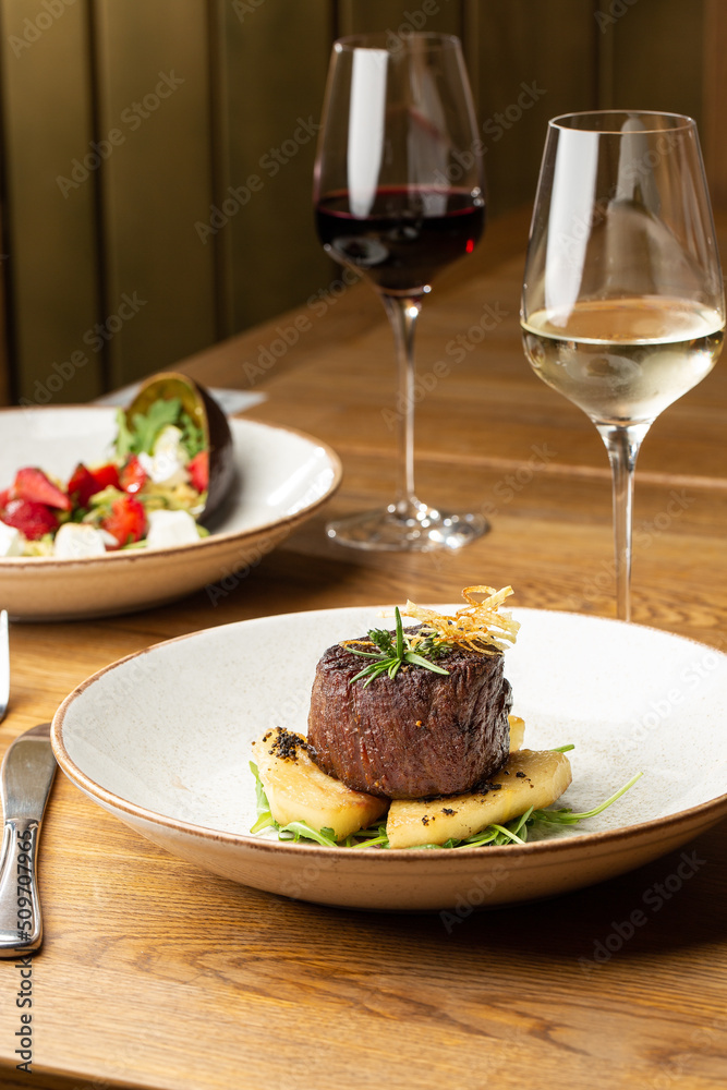 Grilled meat fillet steak medallion with green sauce, served with pear or apple. On dark background