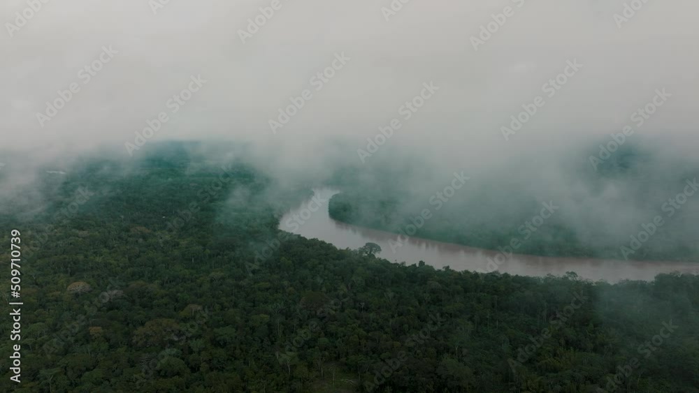 Drone descends through thin cloud over lush Amazon rainforest, meandering river Drone descends through thin cloud over lush Amazon rainforest, meandering river