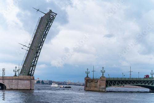 Raised span of movable single-leafed bascule Trinity bridge in Saint Petersburg, cloudy day, view from the side. Upward swing to provide clearance for boat traffic