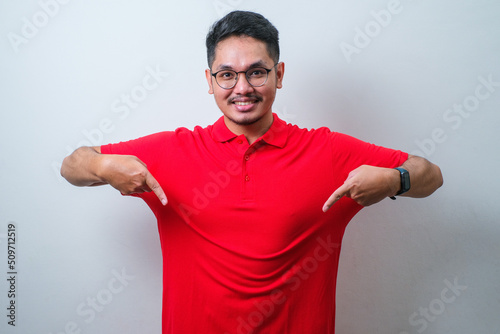 Young asian man wearing casual shirt pointing down with fingers showing advertisement