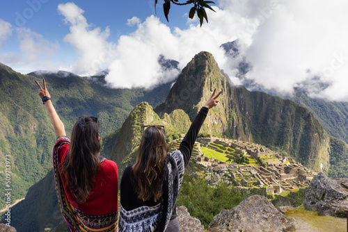 two women celebrating their arrival at machu picchu by raising their arms photo