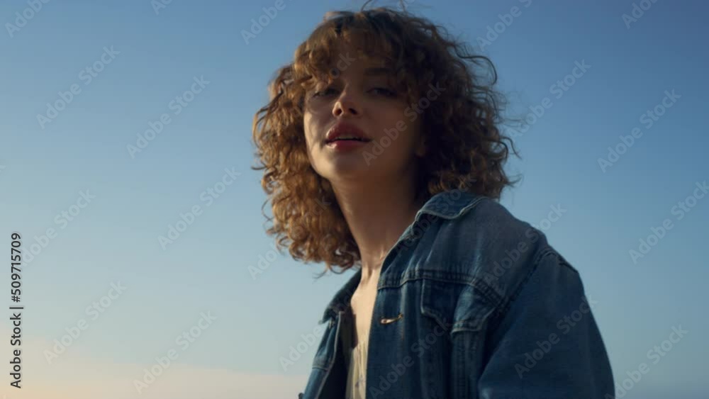Portrait of cheerful woman posing on beach. Elegant girl walking along seacoast Portrait of cheerful woman posing on beach. Elegant girl walking along seacoast