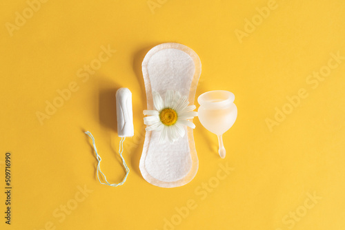 Menstruation period concept. Hygienic white female pad, Menstrual cup and tampon with chamomile flowers. Menstruation, protection. Women's health photo