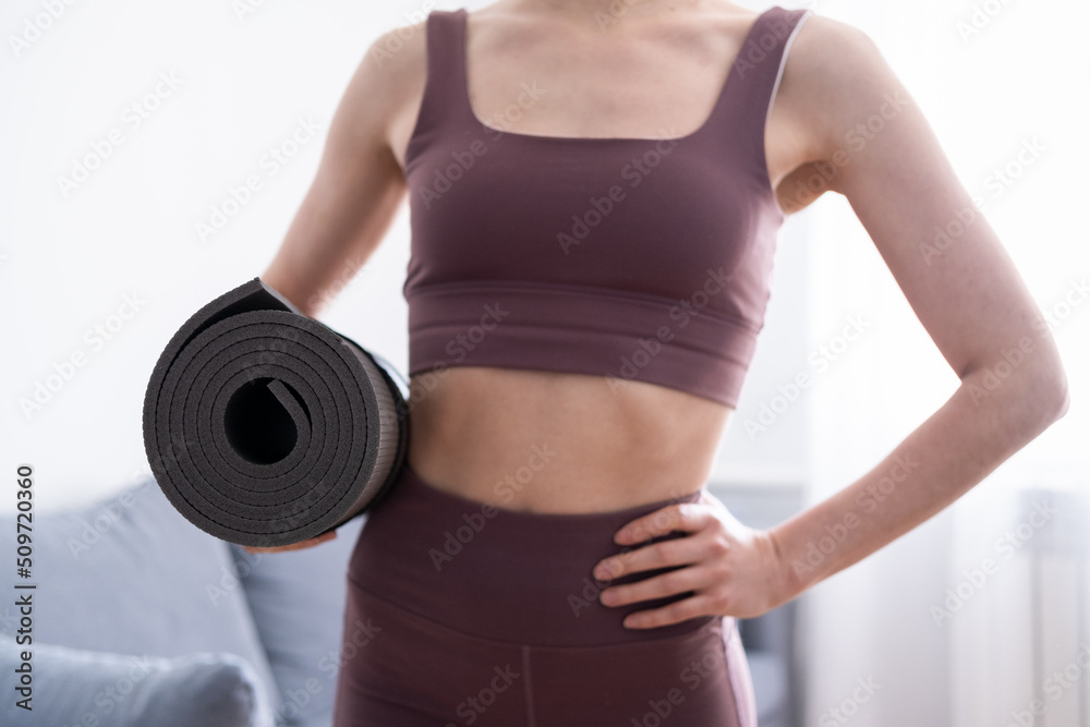 A young girl in a good athletic build holds a mat for sports in her hands A young girl in a good athletic build holds a mat for sports in her hands