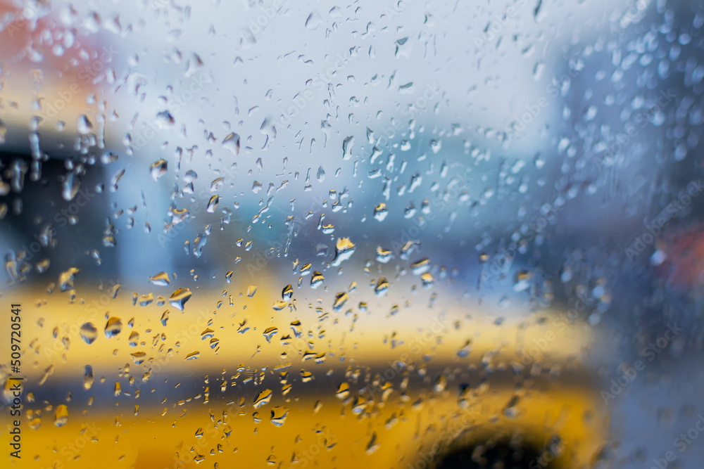 Raindrops falling on glass, abstract blurs - monsoon stock image of traditional yellow taxi of Kolkata (formerly Calcutta) city , West Bengal, India