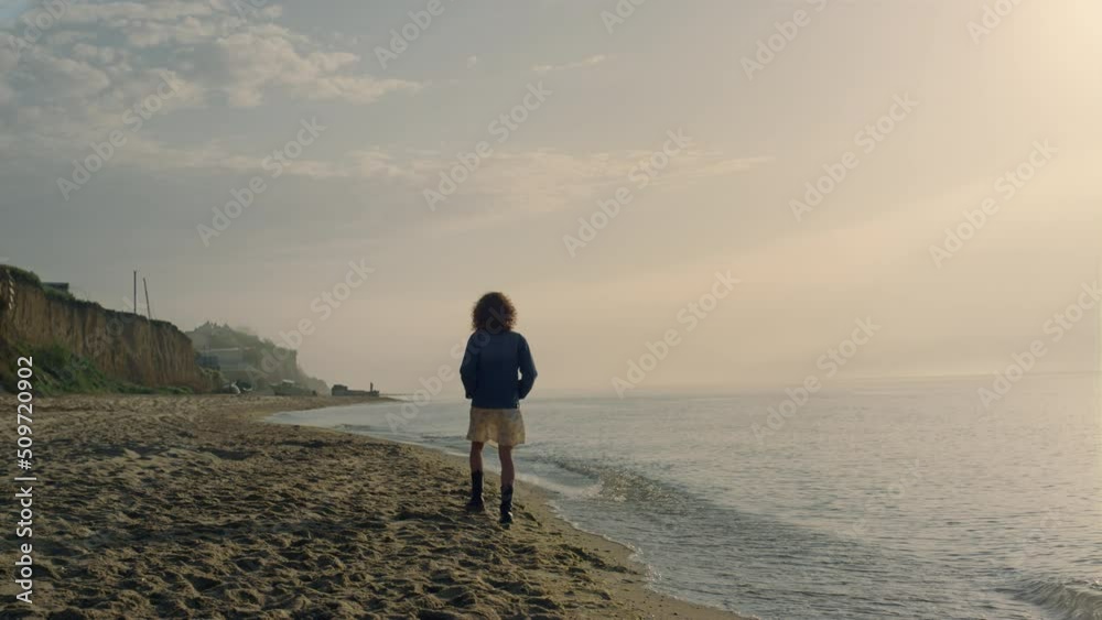Fashionable woman walking on sea shore. Relaxed girl enjoying ocean landscape.