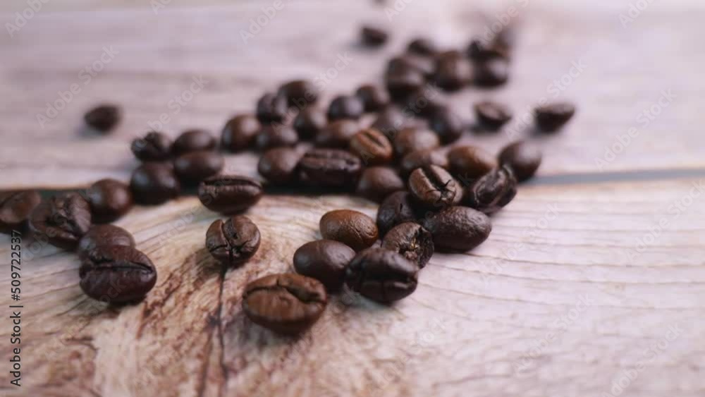 Take a close-up video of coffee beans being poured onto a wooden floor, moving slowly in focus at some point. Provides a warm glow with a warm mood infused with a slight darkness Take a close-up video of coffee beans being poured onto a wooden floor, moving slowly in focus at some point. Provides a warm glow with a warm mood infused with a slight darkness