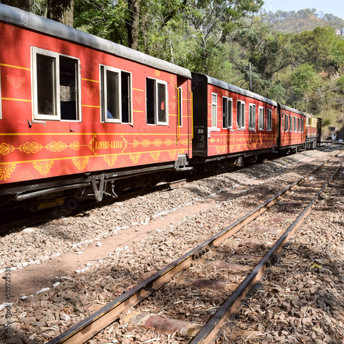 Toy Train moving on mountain slopes, beautiful view, one side mountain, one side valley moving on railway to the hill, among green natural forest. Toy train from Kalka to Shimla in India