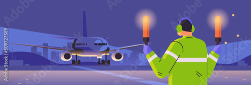 aviation marshaller with light sticks near aircraft air traffic controller airline worker in signal vest professional airport staff photo
