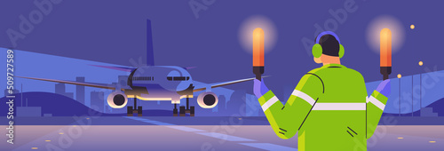 aviation marshaller with light sticks near aircraft air traffic controller airline worker in signal vest professional airport staff